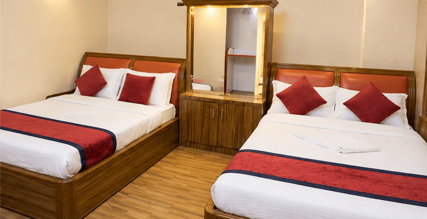 Hotel Taj twin-bed room with two beds, white linen, and burgundy cushions